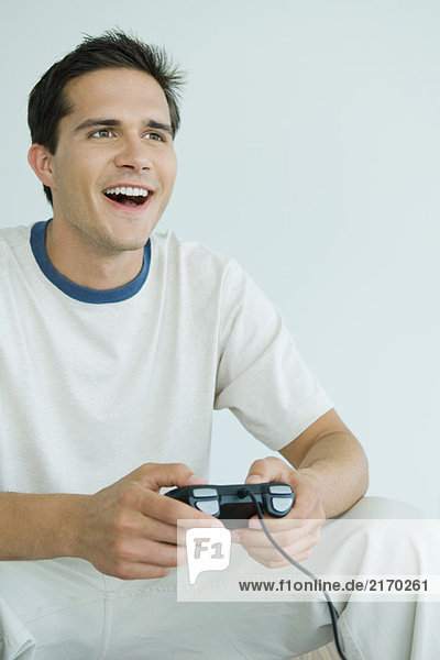 Young man playing video game  looking out of frame  smiling