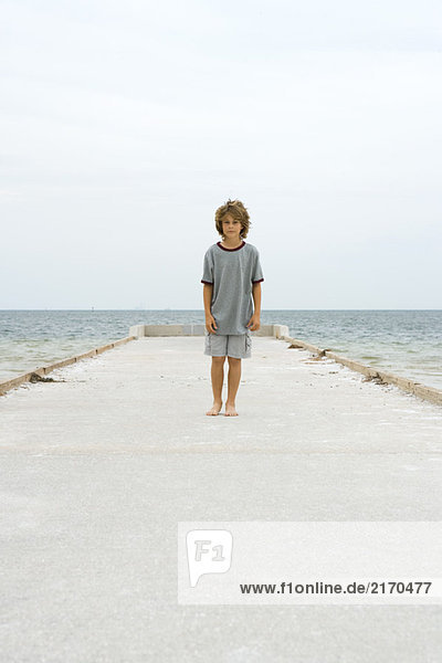 Boy standing on pier  looking at camera