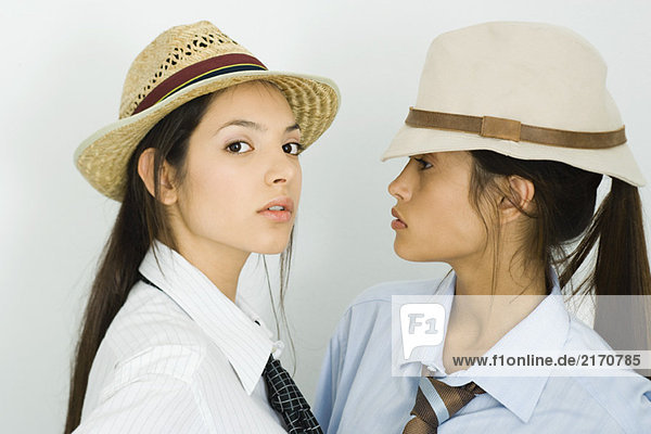 Zwei junge Freundinnen mit Hüten und Krawatten  eine schaut in die Kamera.