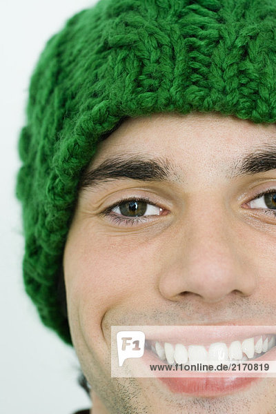 Young man in knit hat smiling at camera  cropped view