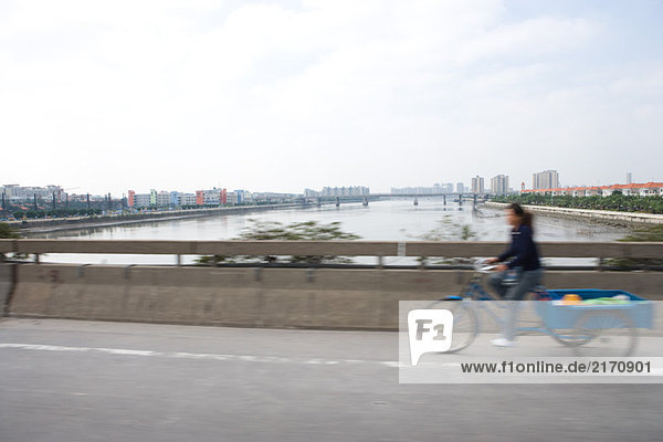 Cyclist with cart crossing bridge  blurred motion