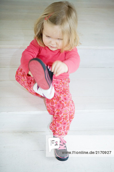Blondes Kleinkind Mädchen beim Anziehen der Schuhe  volle Länge