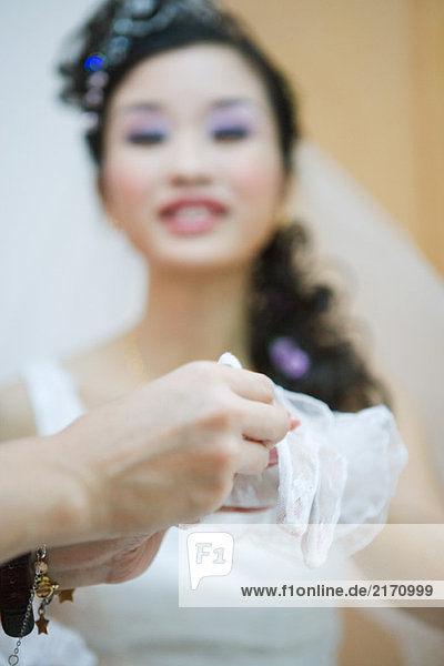 Bride having lace glove put on  cropped view