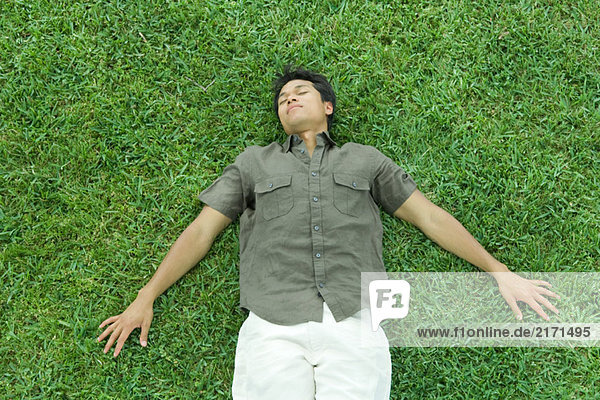 Mann auf dem Rücken im Gras liegend  Augen geschlossen