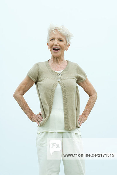Seniorin stehend mit Händen auf den Hüften  lächelnd vor der Kamera  Porträt