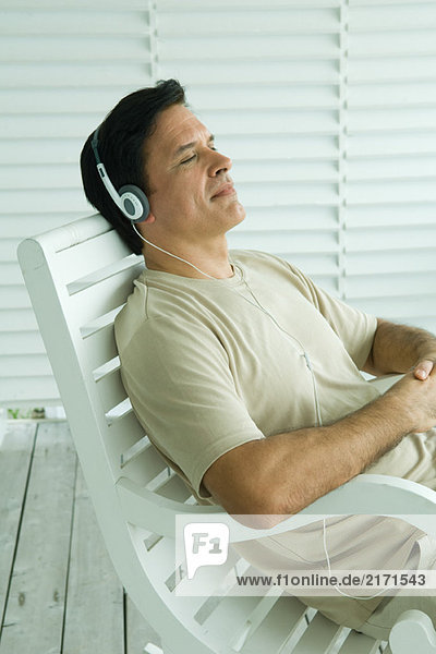 Mann im Schaukelstuhl sitzend  Kopfhörer hörend