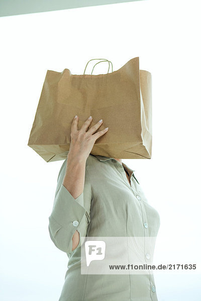 Frau hält Papiertasche auf Schulter  Kopf versteckt