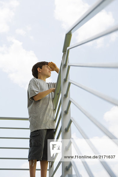 Boy standing on balcony  looking at view  low angle view