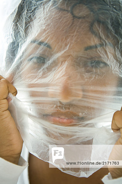 Frau mit Plastiktüte über dem Gesicht  Blick auf die Kamera