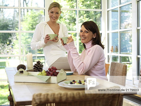 Portrait von zwei Frauen dem Frühstück am Tisch und lächelnd