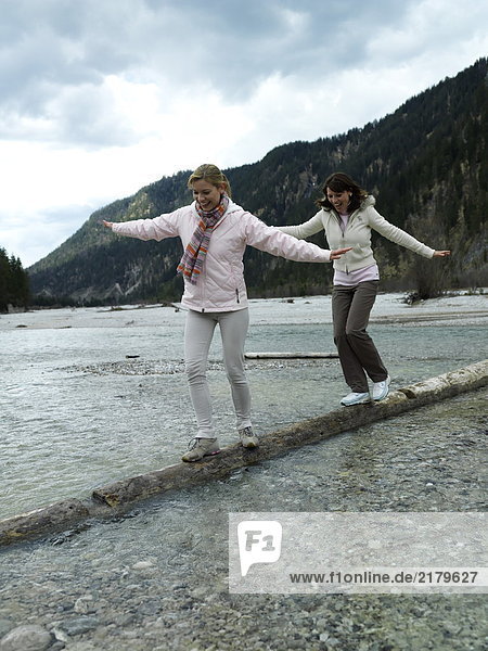 Zwei junge Frauen balancieren auf einloggen river