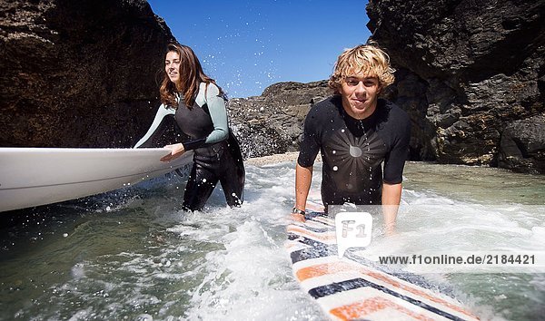 Paar im Wasser stehend mit lächelnden Surfbrettern.