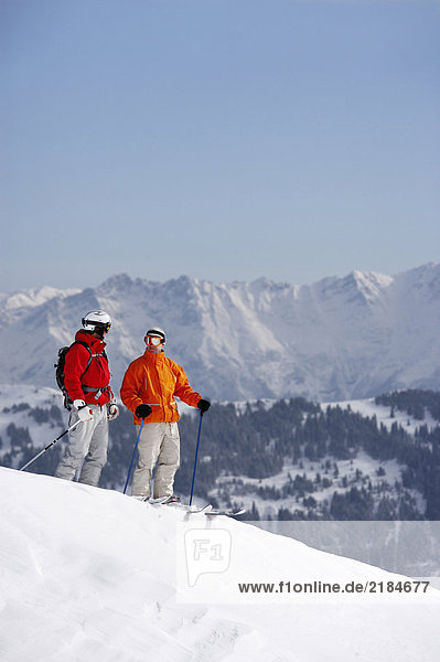 Austria  Saalbach  two skiers standing on slope talking to each other