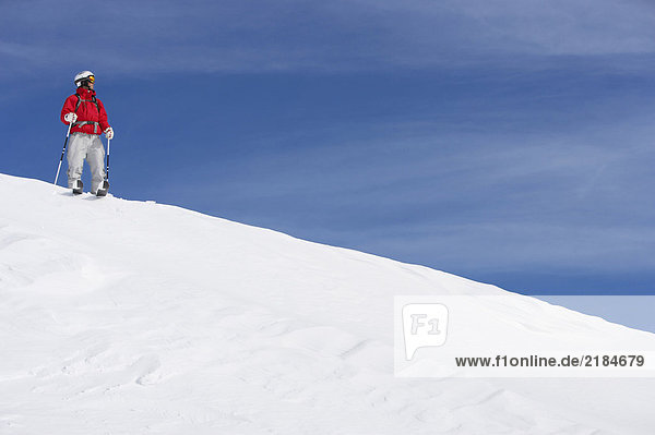 Männlicher Skifahrer auf schneebedeckter Piste stehend