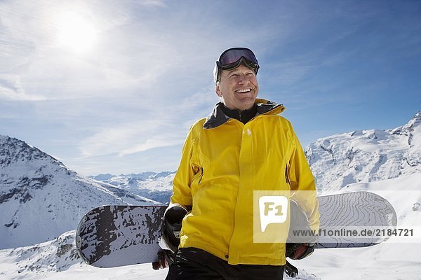Mature male snowboarder with snowboard on mountain  portrait