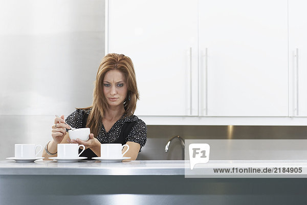Woman in staff kitchen with mugs of coffee