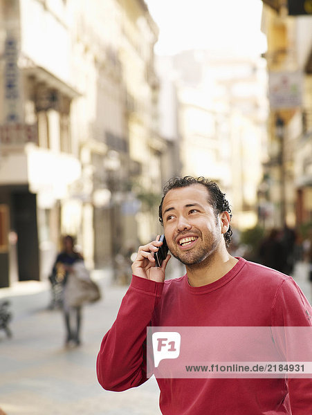 Mann steht auf der Straße mit dem Handy  lächelnd