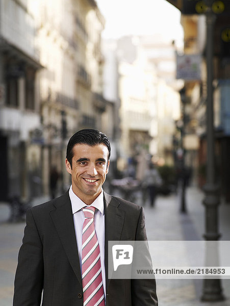 Young businessman standing in street  smiling