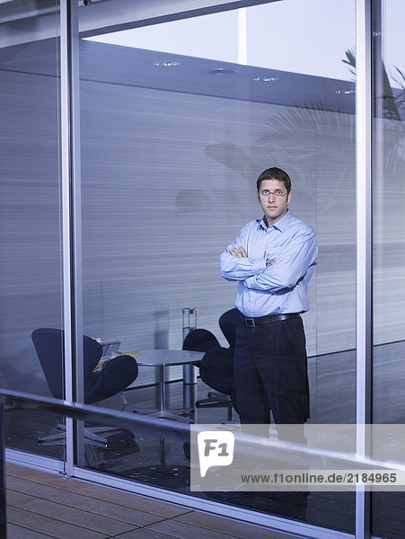 Young businessman standing at window in office  portrait
