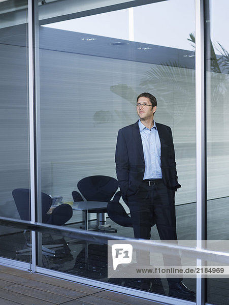 Young businessman standing at window in office