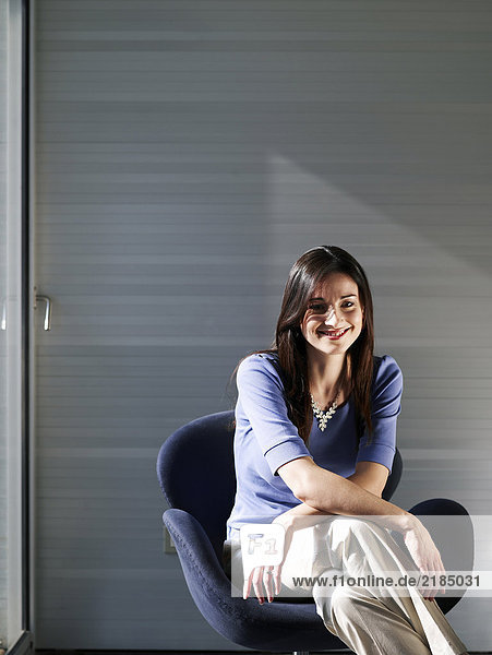 Geschäftsfrau im Büro sitzend  lächelnd  Portrait