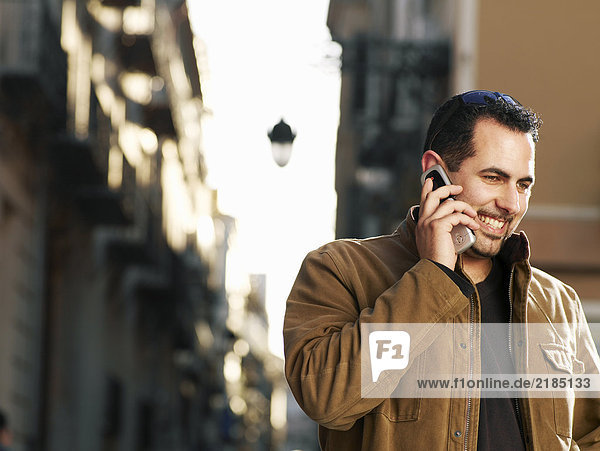 Young man using mobile phone in street  smiling