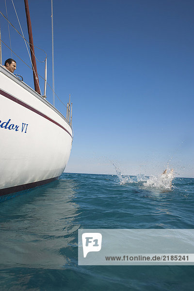 Young woman splashing in sea by yacht