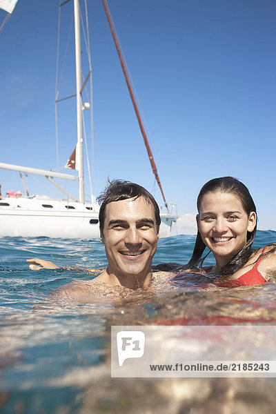 Young couple swimming in sea by yacht  smiling  portrait