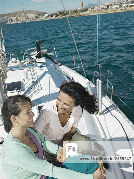 Mature mother and daughter relaxing on yacht  smiling