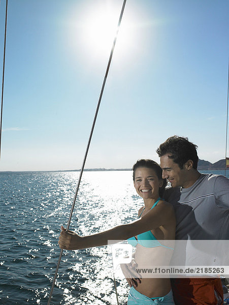 Young couple standing on yacht at sea  smiling