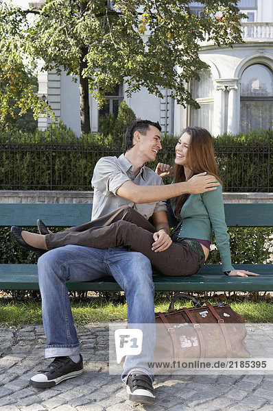 Ein Paar sitzt auf einer Bank und lacht.