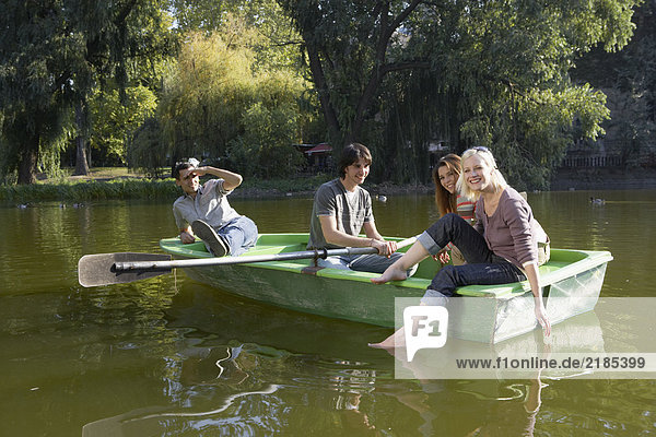Vier Freunde in einem Ruderboot lächeln.