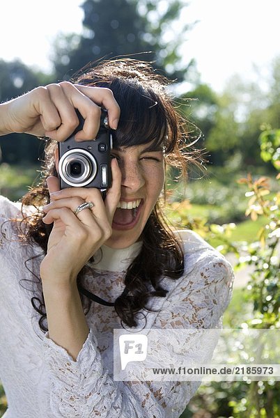 Junge Braut mit Digitalkamera im Garten  lächelnd  Nahaufnahme