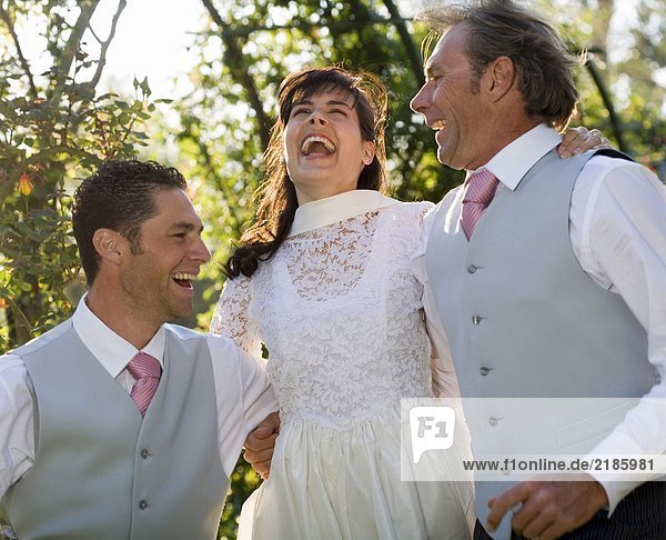 Junge Braut und Bräutigam und reifer Vater springen  lächelnd