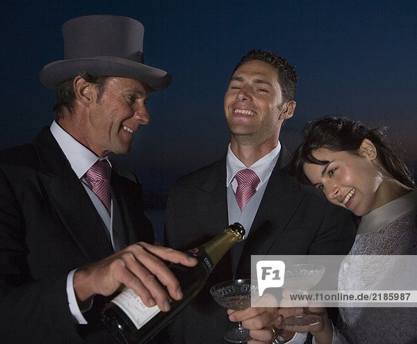 Braut und Bräutigam und reifer Vater mit Champagner  lächelnd