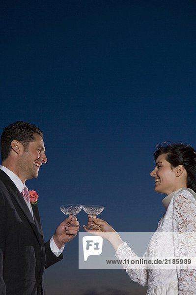 Braut und Bräutigam toasten sich gegenseitig mit Champagner  lächeln  Sonnenuntergang
