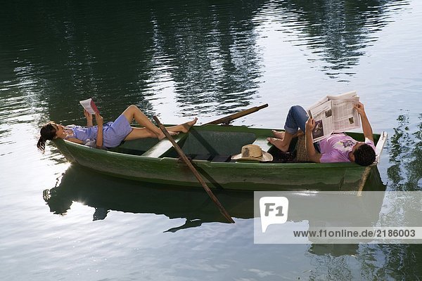Mann und Frau liegend und lesend in einem Boot