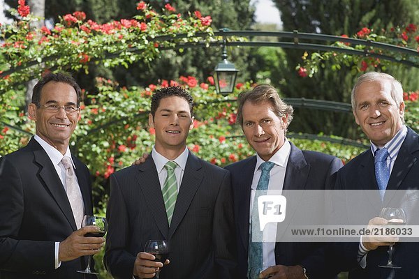 Four businessmen drinking wine in a garden