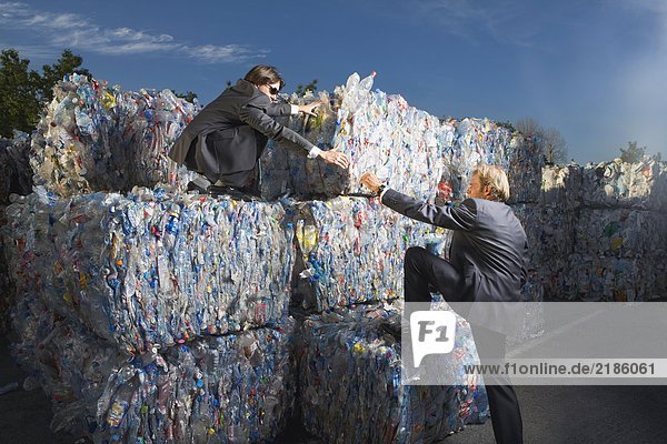 Geschäftsleute klettern auf eine Mauer des Recyclings.