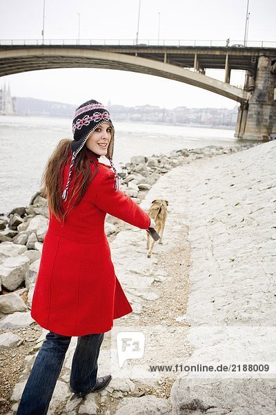 Junge Frau  die am Fluss spazieren geht  über die Schulter schaut  lächelt