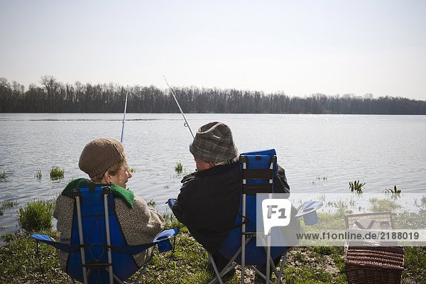 Senior couple fishing together by river  rear view
