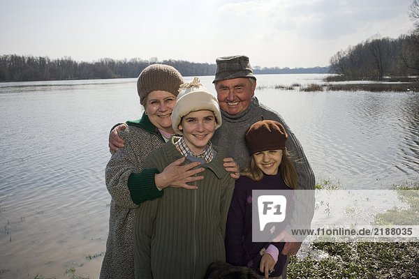 Grandparents standing by river with grandson (12-14) and grangdaughter (11-13) smiling