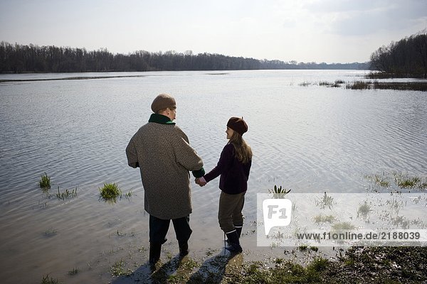 Grandmother and granddaughter (10-12) standing in river  rear view
