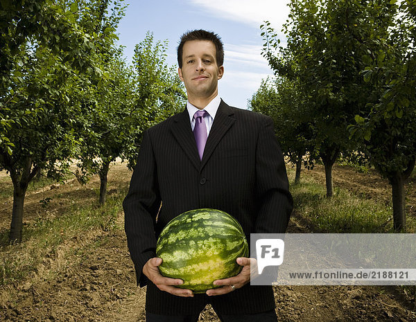 Mann mit Melone im Obstgarten.