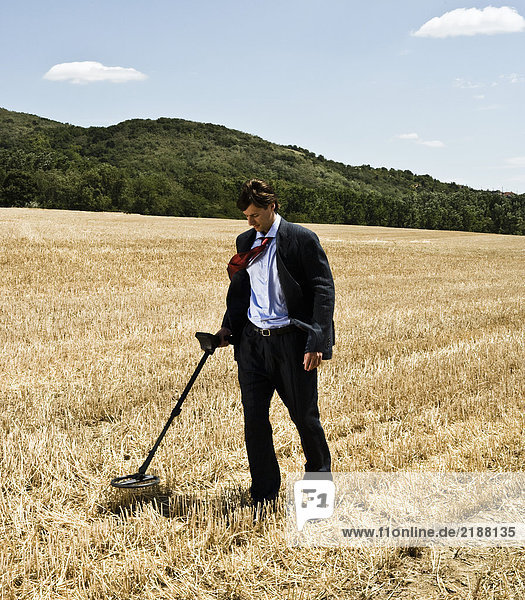 Businessman with metal detector outdoors.