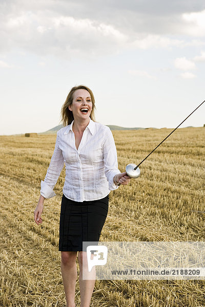 Geschäftsfrau Fechten in einem Weizenfeld.
