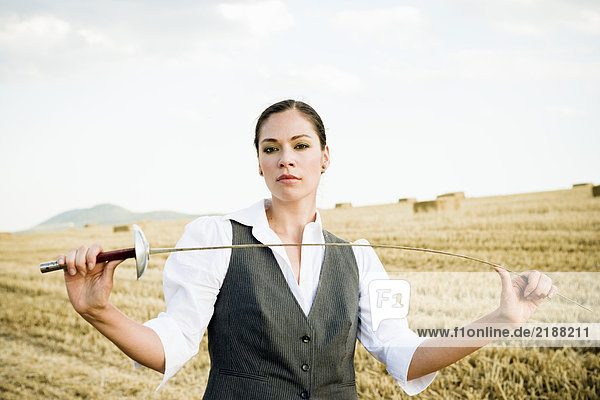 Geschäftsfrau Fechten in einem Weizenfeld.