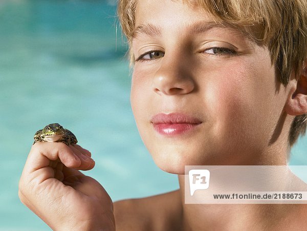 Ein Junge hält einen Frosch in der Hand.