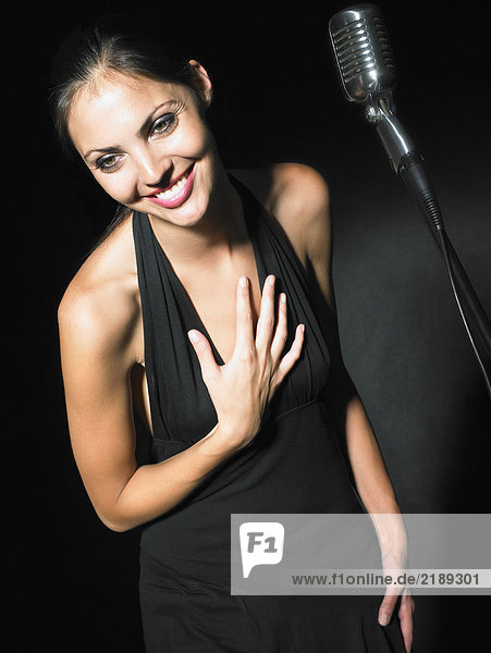 Female singer with microphone elegant black dress portrait.
