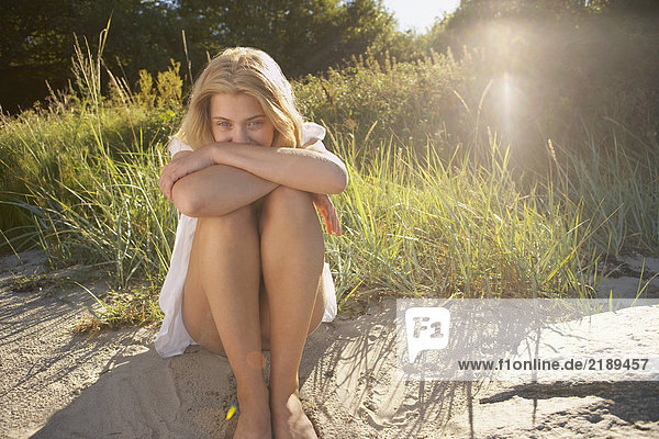 Junge Frau sitzt am Rande des Strandes.